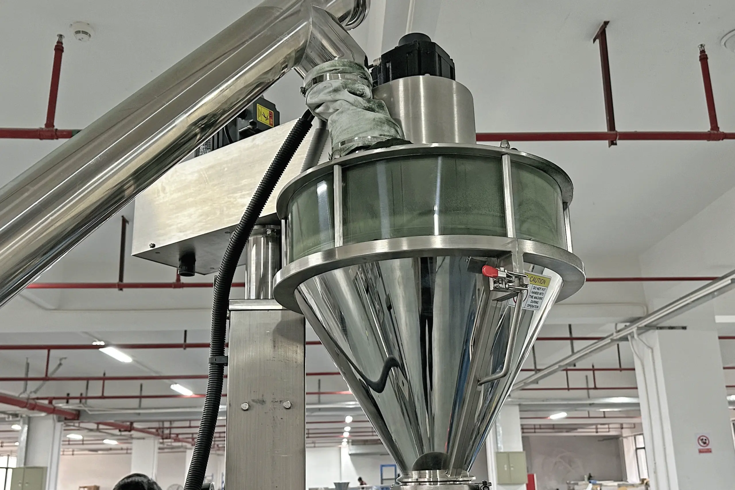 Matcha powder packaging machine hopper and funnel seen at a 45 degree angle in a food factory
